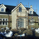 Man of scaffold working on plastering a house