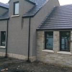New home light grey walls with blue slate roof and stone effect walls